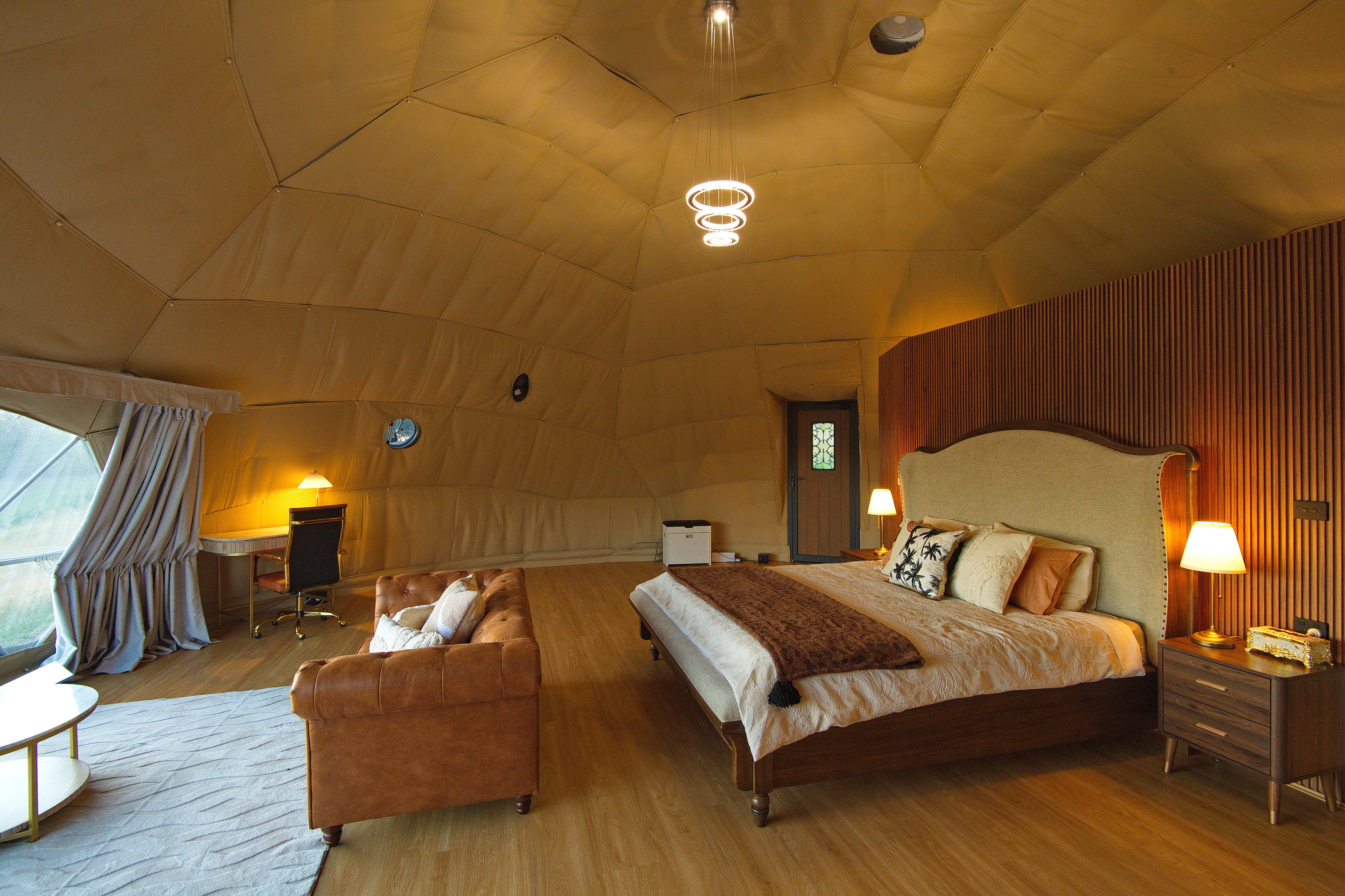 Luxury glamping dome interior with king bed and warm lighting
